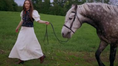 Huzurlu orman ortamında at besleyen bir kadın. Kadının yürüdüğü ve atla ağaçlar arasında bağ kurduğu huzurlu bir an. Sakin orman sahnesinde at ve kadın arasındaki bağ. Tarlada atlara sevgi gösteren bir kadın. At okşayan kadın. 