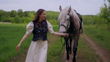 Huzurlu orman ortamında at besleyen bir kadın. Kadının yürüdüğü ve atla ağaçlar arasında bağ kurduğu huzurlu bir an. Sakin orman sahnesinde at ve kadın arasındaki bağ. Tarlada atlara sevgi gösteren bir kadın. At okşayan kadın. 