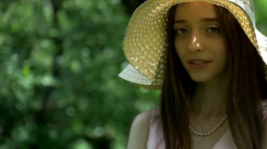 Bahçedeki ağaçların arasında duran pembe elbiseli ve hasır şapkalı kız. Park ortamında gülümseyen pembe elbiseli genç bir kız. Ormanda ağaçlarla çevrili pembe elbiseli bir kız. Pembe elbiseli kız yemyeşil ormanda dikiliyor.. 