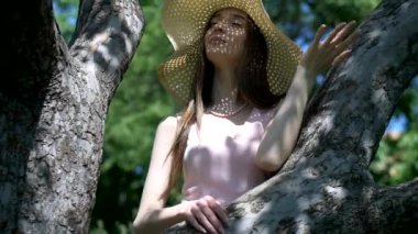 Bahçedeki ağaçların arasında duran pembe elbiseli ve hasır şapkalı kız. Park ortamında gülümseyen pembe elbiseli genç bir kız. Ormanda ağaçlarla çevrili pembe elbiseli bir kız. Pembe elbiseli kız yemyeşil ormanda dikiliyor.. 