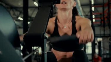 Spor salonundaki bir kız. Seksi genç kadın spor salonunda simülatörlerle meşgul. Güzel spor figürü. Güçlü bir atlet spor salonunda aktif olarak spor yapmaktadır. Spor salonunda spor yapan spor meraklısı. Jimnastik. Etki halindeki kuvvet eğitimi.