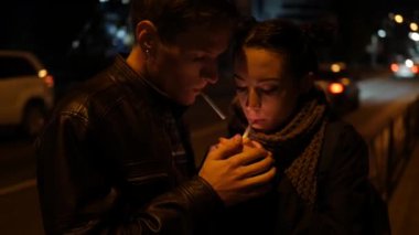 Erkek ve kız sigara içiyor. Sevgi dolu bir çift gece sokakta sigara içer. Bir erkek ve bir kadın sigara içiyorlar. Birbirine aşık bir çift, gece sokağının ortasında sarılıyor..