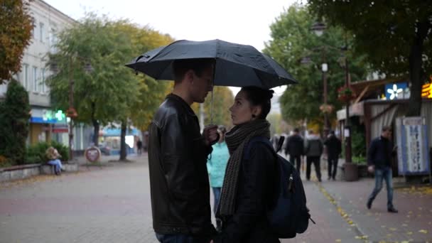 男と女の子は傘の下に立っている 恋するカップル 通りの真ん中に傘の下に男と女が立っている — ストック動画
