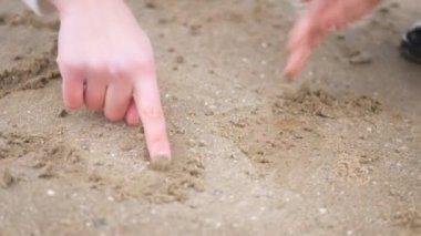Anne ve kızı su kenarında birbirlerine sarılıp duruyorlar. Kadın ve çocuğun manzaranın tadını çıkardığı plaj sahnesi. Kadın ve kız gülümsüyor ve sahilde duruyor, denize bakıyor. Kadın ve küçük kız sahilde ufka bakıyor. Kumlu sahilde aile zamanı
