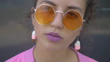 Tuhaf pembe elbiseli bir kadın binanın önünde neşeyle şarkı söylüyor. Pembe elbiseli canlı bir kadın bir binanın yakınında dans figürleri sergiliyor. Pembe ceketli ve şortlu biri bir binanın yanında enerjik bir şekilde şarkı söylüyor. Pembe elbiseli, neşeli bir kadın. 