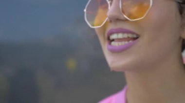 Tuhaf pembe elbiseli bir kadın binanın önünde neşeyle şarkı söylüyor. Pembe elbiseli canlı bir kadın bir binanın yakınında dans figürleri sergiliyor. Pembe ceketli ve şortlu biri bir binanın yanında enerjik bir şekilde şarkı söylüyor. Pembe elbiseli, neşeli bir kadın. 