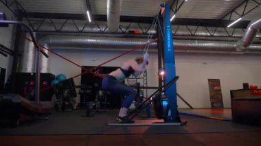 Beden eğitiminde fiziksel egzersiz yapan bir kadın. Kadın spor salonunda ağırlıklı çömelme yapıyor. Aktif bayan spor salonunda dambıllarla çömeliyor. Kadın bacak egzersizi için çömeliyor. Spor meraklısı düzgün bir şekilde çömeliyor. Sportif Kadın  