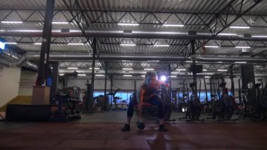 Beden eğitiminde fiziksel egzersiz yapan bir kadın. Kadın spor salonunda ağırlıklı çömelme yapıyor. Aktif bayan spor salonunda dambıllarla çömeliyor. Kadın bacak egzersizi için çömeliyor. Spor meraklısı düzgün bir şekilde çömeliyor. Sportif Kadın  