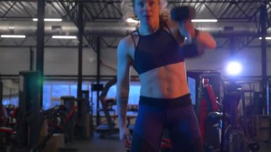 Beden eğitiminde fiziksel egzersiz yapan bir kadın. Kadın spor salonunda ağırlıklı çömelme yapıyor. Aktif bayan spor salonunda dambıllarla çömeliyor. Kadın bacak egzersizi için çömeliyor. Spor meraklısı düzgün bir şekilde çömeliyor. Sportif Kadın  