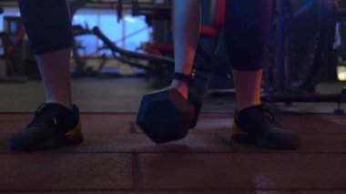 Beden eğitiminde fiziksel egzersiz yapan bir kadın. Kadın spor salonunda ağırlıklı çömelme yapıyor. Aktif bayan spor salonunda dambıllarla çömeliyor. Kadın bacak egzersizi için çömeliyor. Spor meraklısı düzgün bir şekilde çömeliyor. Sportif Kadın  
