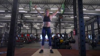 Beden eğitiminde fiziksel egzersiz yapan bir kadın. Kadın spor salonunda ağırlıklı çömelme yapıyor. Aktif bayan spor salonunda dambıllarla çömeliyor. Kadın bacak egzersizi için çömeliyor. Spor meraklısı düzgün bir şekilde çömeliyor. Sportif Kadın  