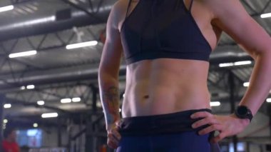 Beden eğitiminde fiziksel egzersiz yapan bir kadın. Kadın spor salonunda ağırlıklı çömelme yapıyor. Aktif bayan spor salonunda dambıllarla çömeliyor. Kadın bacak egzersizi için çömeliyor. Spor meraklısı düzgün bir şekilde çömeliyor. Sportif Kadın  