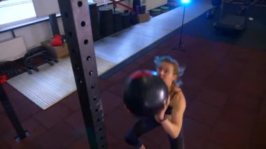 Beden eğitiminde fiziksel egzersiz yapan bir kadın. Kadın spor salonunda ağırlıklı çömelme yapıyor. Aktif bayan spor salonunda dambıllarla çömeliyor. Kadın bacak egzersizi için çömeliyor. Spor meraklısı düzgün bir şekilde çömeliyor. Sportif Kadın  