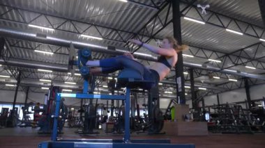 Beden eğitiminde fiziksel egzersiz yapan bir kadın. Kadın spor salonunda ağırlıklı çömelme yapıyor. Aktif bayan spor salonunda dambıllarla çömeliyor. Kadın bacak egzersizi için çömeliyor. Spor meraklısı düzgün bir şekilde çömeliyor. Sportif Kadın  