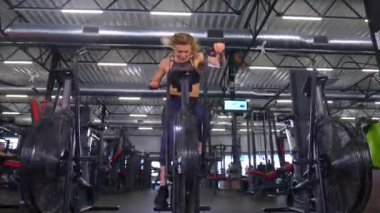 Beden eğitiminde fiziksel egzersiz yapan bir kadın. Kadın spor salonunda ağırlıklı çömelme yapıyor. Aktif bayan spor salonunda dambıllarla çömeliyor. Kadın bacak egzersizi için çömeliyor. Spor meraklısı düzgün bir şekilde çömeliyor. Sportif Kadın  