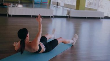 Bir kadın fiziksel egzersiz yapıyor. Genç bir kız kaslarını esneterek hücum eder. Spor salonunda spor mankeni. Güzel vücutlu bir kadın paspasın üzerinde fiziksel egzersiz yapar.. 