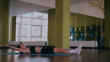 Bir kadın fiziksel egzersiz yapıyor. Genç bir kız kaslarını esneterek hücum eder. Spor salonunda spor mankeni. Güzel vücutlu bir kadın paspasın üzerinde fiziksel egzersiz yapar.. 