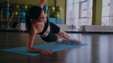 Bir kadın fiziksel egzersiz yapıyor. Genç bir kız kaslarını esneterek hücum eder. Spor salonunda spor mankeni. Güzel vücutlu bir kadın paspasın üzerinde fiziksel egzersiz yapar.. 