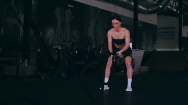 Atlet bir iple egzersiz yapar. Spor salonundaki bir kız. Seksi genç kadın spor salonunda simülatörlerle meşgul. Güzel spor figürü..