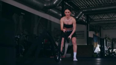 Atlet bir iple egzersiz yapar. Spor salonundaki bir kız. Seksi genç kadın spor salonunda simülatörlerle meşgul. Güzel spor figürü..