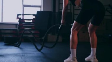 Atlet bir iple egzersiz yapar. Spor salonundaki bir kız. Seksi genç kadın spor salonunda simülatörlerle meşgul. Güzel spor figürü..