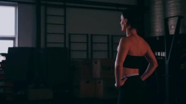 Spor salonunda çalışan ve kameraya poz veren bir kız. Seksi kadın model spor salonunda simülatörlere bağlanır. Güzel spor figürü..