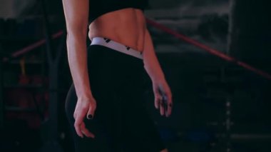 Spor salonunda çalışan ve kameraya poz veren bir kız. Seksi kadın model spor salonunda simülatörlere bağlanır. Güzel spor figürü..