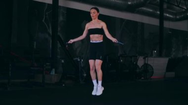 Sporcu bir ipe atlıyor. Spor salonundaki bir kız. Seksi genç kadın spor salonunda simülatörlerle meşgul. Güzel spor figürü..