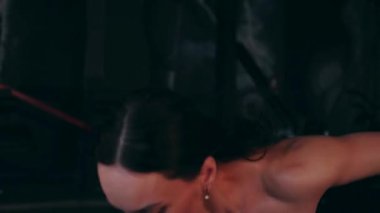 Spor salonunda çalışan ve kameraya poz veren bir kız. Seksi kadın model spor salonunda simülatörlere bağlanır. Güzel spor figürü..