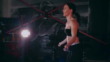 Sporcu bir ipe atlıyor. Spor salonundaki bir kız. Seksi genç kadın spor salonunda simülatörlerle meşgul. Güzel spor figürü..