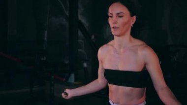 Sporcu bir ipe atlıyor. Spor salonundaki bir kız. Seksi genç kadın spor salonunda simülatörlerle meşgul. Güzel spor figürü..