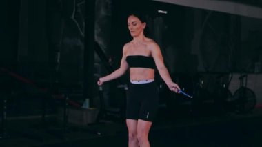 Sporcu bir ipe atlıyor. Spor salonundaki bir kız. Seksi genç kadın spor salonunda simülatörlerle meşgul. Güzel spor figürü..