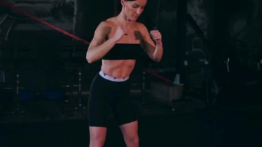 Spor salonunda çalışan ve kameraya poz veren bir kız. Seksi kadın model spor salonunda simülatörlere bağlanır. Güzel spor figürü..
