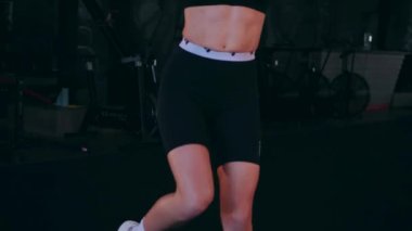 Spor salonunda çalışan ve kameraya poz veren bir kız. Seksi kadın model spor salonunda simülatörlere bağlanır. Güzel spor figürü..