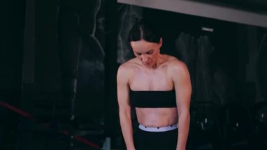 Spor salonunda çalışan ve kameraya poz veren bir kız. Seksi kadın model spor salonunda simülatörlere bağlanır. Güzel spor figürü..