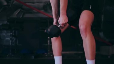 Spor salonunda dambıllı bir kız antrenman yapıyor. Seksi kadın model spor salonunda simülatörlere bağlanır. Güzel spor figürü..