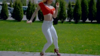 Güzel enerjik kadın dışarıda salsa yapıyor. Bachata yapan genç bir kadın, açık gökyüzünün altında parkta kizomba yapıyor. Şehrin kaldırımında ateşli bir kadının baştan çıkarıcı dansı..