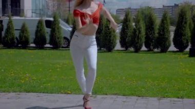 Güzel enerjik kadın dışarıda salsa yapıyor. Bachata yapan genç bir kadın, açık gökyüzünün altında parkta kizomba yapıyor. Şehrin kaldırımında ateşli bir kadının baştan çıkarıcı dansı..