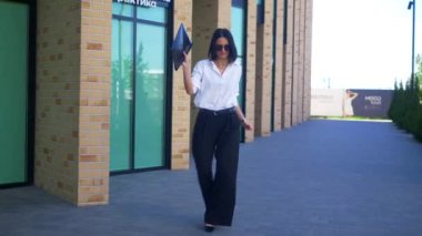 İş kadını iş merkezinin yakınında dans edip gülümsüyor. Ofis çalışanı, yönetmen, resmi kıyafetler. Beyaz gömlekli ve siyah pantolonlu bir kadın işi bittikten sonra caddenin ortasında dans ediyor. İş gülümseyen girişimci. 