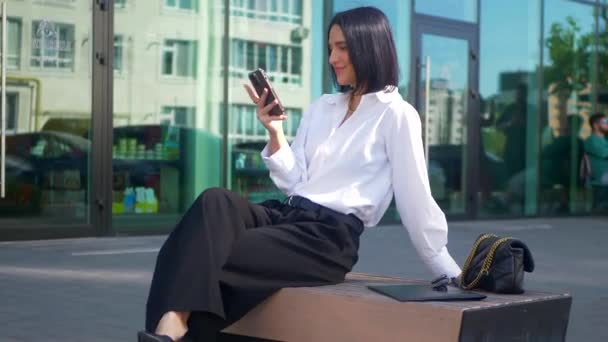 비즈니스 벤치에 앉아있는 전화로 말하는 사무원 형식적인 셔츠와 벤치에 바지에 비디오 클립