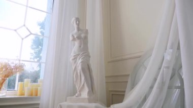 Pencerenin yanındaki zarif heykel. Parlak bir pencereye karşı heykel. Pencereden dışarı bakan heykel. Pencere kenarında tefekkür eden heykel. Heykel ile pencere görünümü