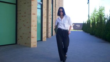 İş kadını iş merkezinin yakınında dans edip gülümsüyor. Ofis çalışanı, yönetmen, resmi kıyafetler. Beyaz gömlekli ve siyah pantolonlu bir kadın işi bittikten sonra caddenin ortasında dans ediyor. İş gülümseyen girişimci. 