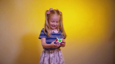 Küçük bir kız hevesle toplarla çocuk mantık oyunu oynuyor. Mutlu bir çocuk sarı arka planda çocuk yapbozu oynuyor. Küçük bir çocuk gülüyor ve mutlu bir oyun oynuyor..