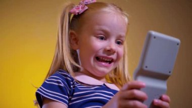 Küçük bir kız heyecanla çocuk oyunu oynuyor Tetris. Mutlu bir çocuk sarı arka planda çocuk yapbozu oynuyor. Küçük bir çocuk gülüyor ve mutlu bir oyun oynuyor..