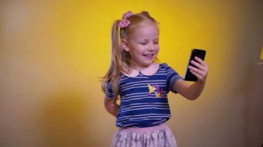 Çocuk telefondaki video konuşmasında eğleniyor gibi. Elinde akıllı telefon kamerasıyla gülümseyen kız. Genç bir kız arıyor ve telefonuyla fotoğraf çekiyor. Küçük kız fotoğraf çekmek için telefonunu kullanıyor. Telefonu olan kız, anıları yakalıyor.
