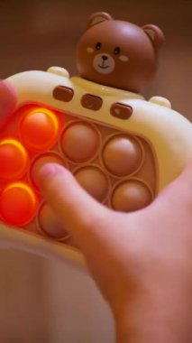 Küçük bir kız hevesle pop it oyunu oynuyor. Dikey video. Pop Fidget Toy 'u it. Mutlu bir çocuk sarı arka planda bir çocuk oyunu oynuyor. Küçük bir çocuk gülüyor ve mutlu bir oyun oynuyor..