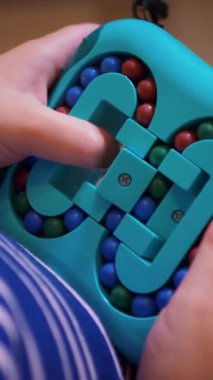 Dikey video. Küçük bir kız hevesle toplarla çocuk mantık oyunu oynuyor. Mutlu bir çocuk sarı arka planda çocuk yapbozu oynuyor. Küçük bir çocuk gülüyor ve mutlu bir oyun oynuyor..