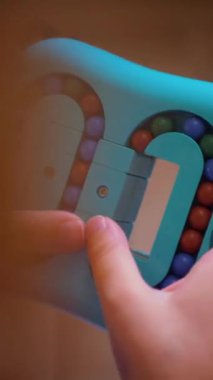 Dikey video. Küçük bir kız hevesle toplarla çocuk mantık oyunu oynuyor. Mutlu bir çocuk sarı arka planda çocuk yapbozu oynuyor. Küçük bir çocuk gülüyor ve mutlu bir oyun oynuyor..