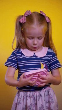 Küçük bir kız hevesle pop it oyunu oynuyor. Dikey video. Pop Fidget Toy 'u it. Mutlu bir çocuk sarı arka planda bir çocuk oyunu oynuyor. Küçük bir çocuk gülüyor ve mutlu bir oyun oynuyor..