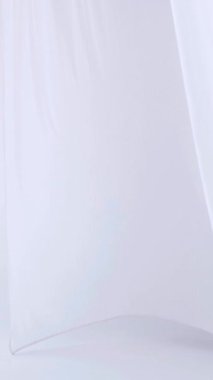 Beyaz şeffaf kumaş rüzgarda dalgalanıyor. Dikey. Parlak bir stüdyoda uzun beyaz perdeler. Rüzgarda savrulan saf beyaz perdeler. Ağır çekim. Görüntüler. Güneşli bir odada beyaz bir perde yükseliyor. Yumuşak, dalgalı beyaz perde huzur içinde 